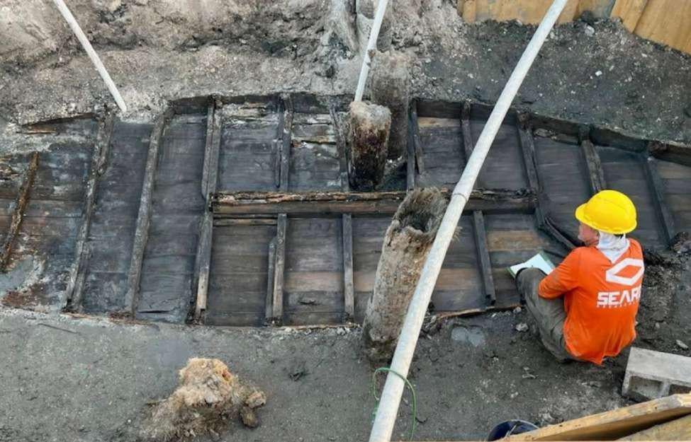 Excavation crews work to dig up a preserved 19th-century boat buried beneath Florida’s busy streets