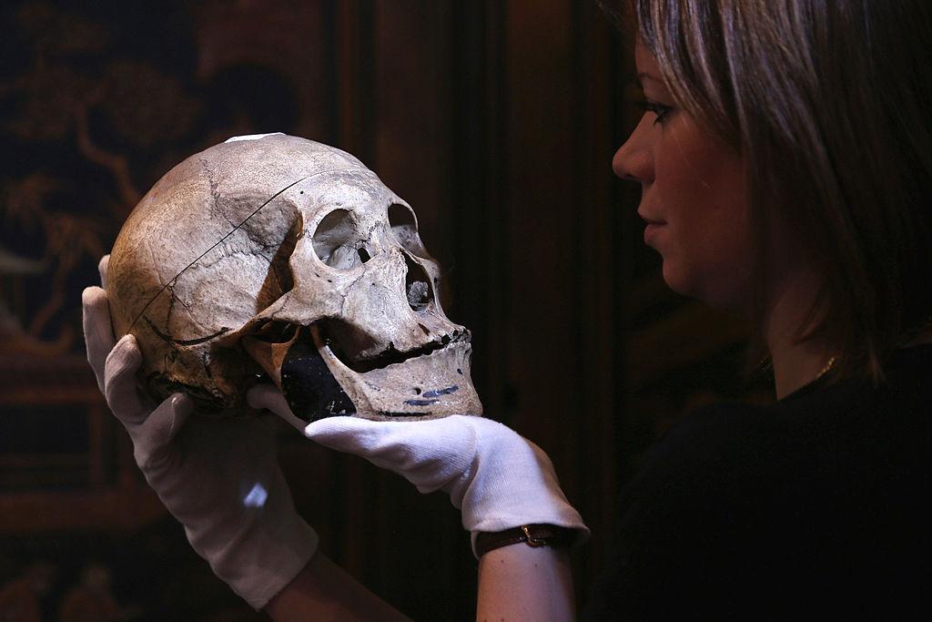 Woman with white gloves holding a human skull