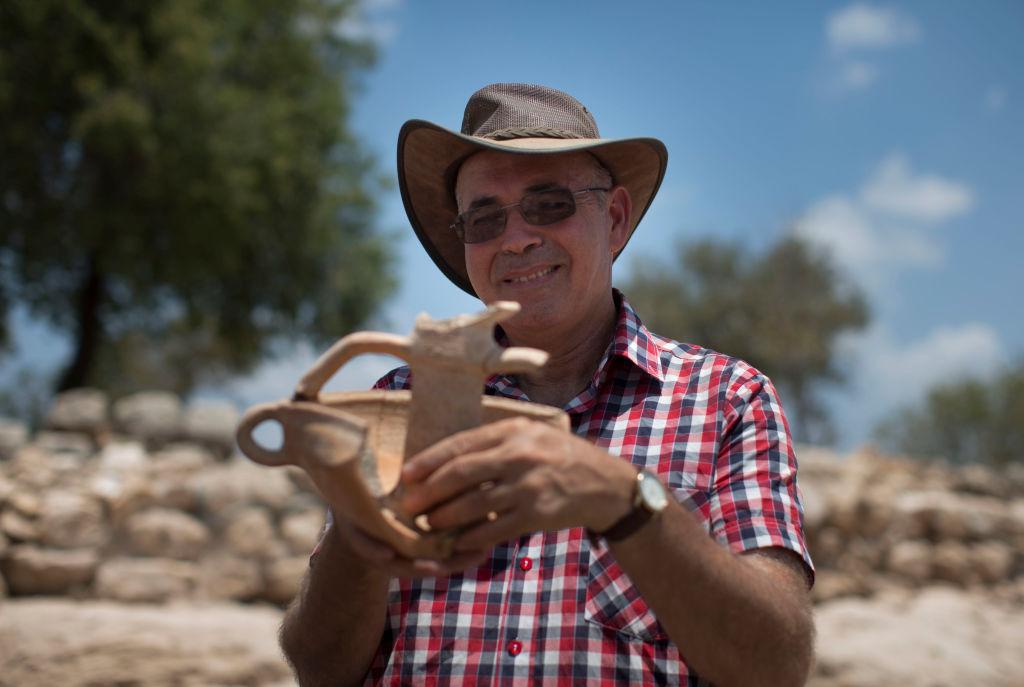 Professor Yosef Garfinkel holds an article from his archaeological excavation next to the remains of what is thought to be King David's palace