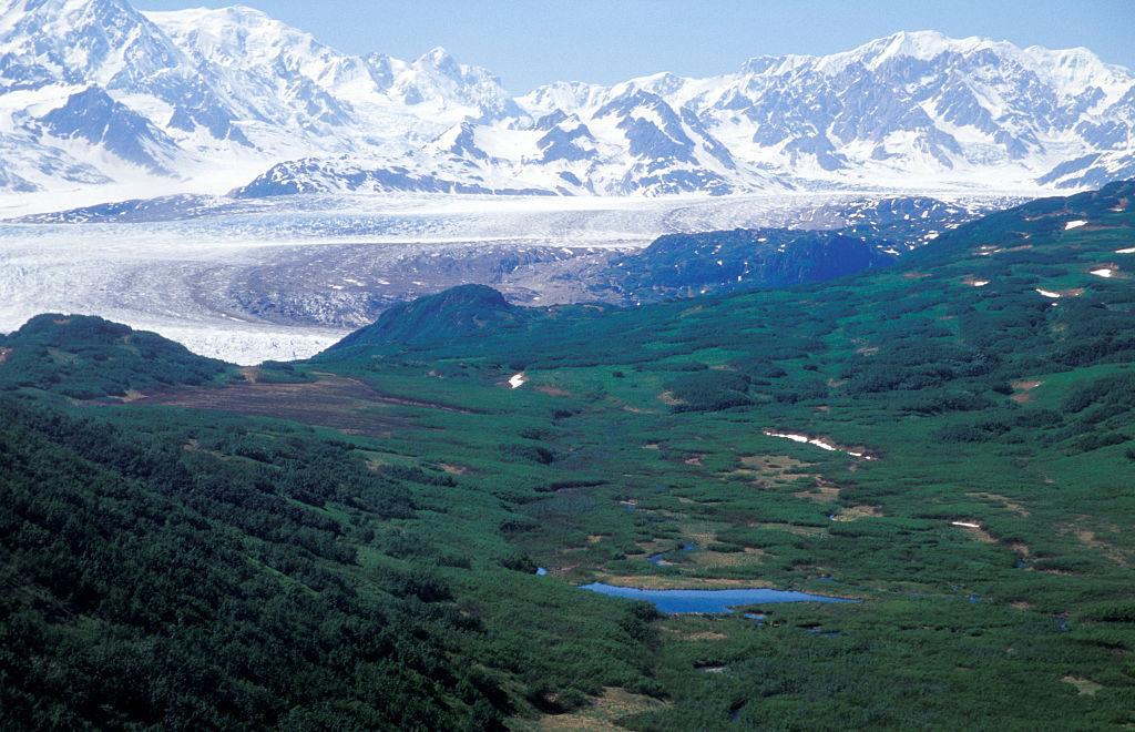 A view of The Triumvirate Glacier in Alaska from a helicopter with mountains in the background