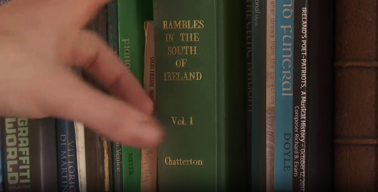Billy Mag Fhloinn selecting “Rambles of the South of Ireland” off his shelf