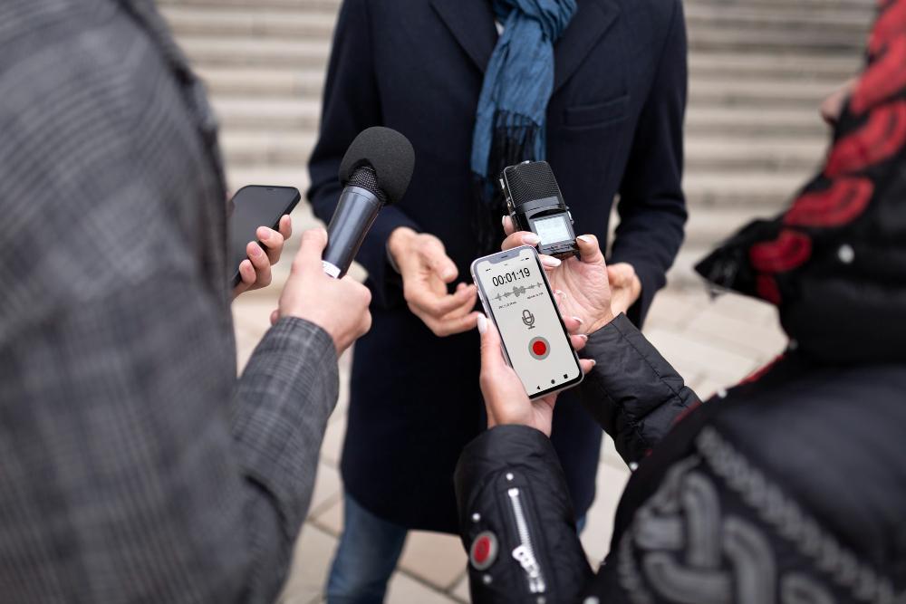 A group of reporters gather around a person on the street to ask questions