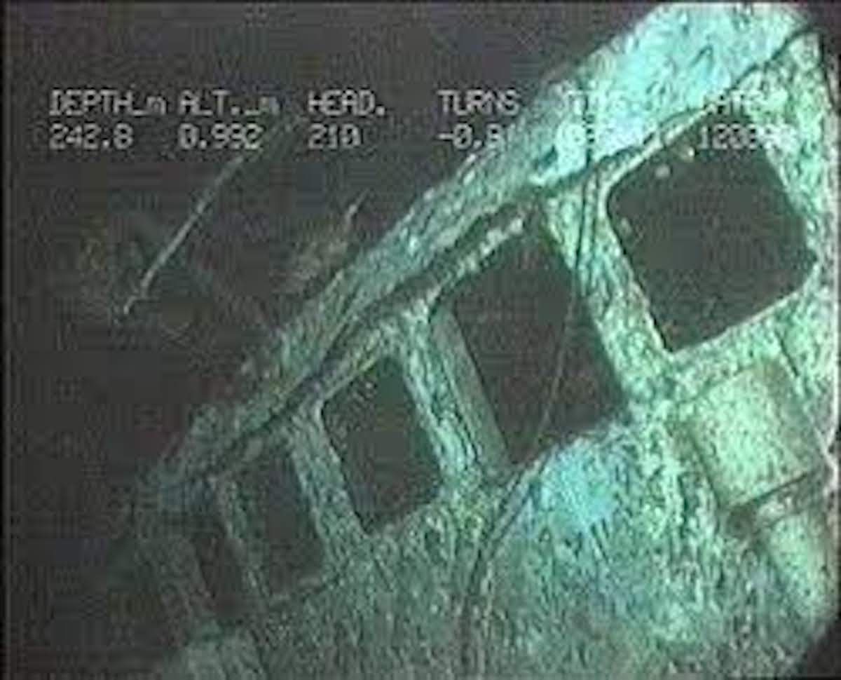 A close-up still of a camera using night vision to look over the wreckage of a ship underwater