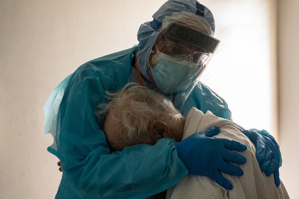 Doctor hugs a COVD-19 patient in full protective gear