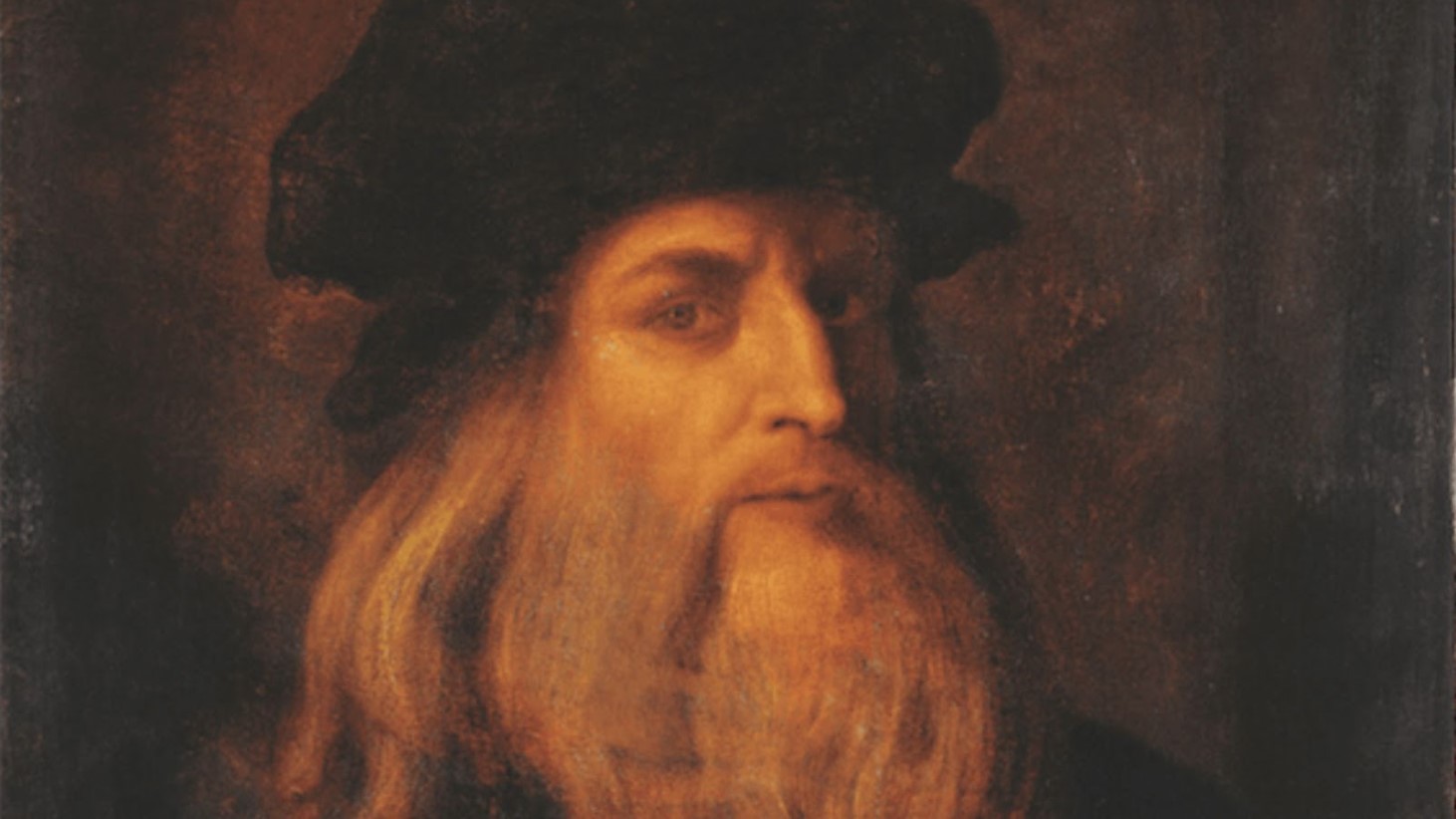 A close-up portrait of the famed Renaissance figure, Leonardo da Vinci, depicted with a thoughtful expression. He has long, wavy hair and a full beard, both rendered in warm tones