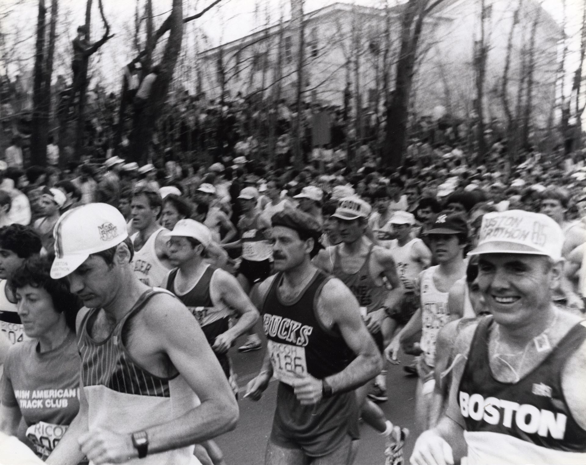 A grey scale image of a group of people running through the streets in a race