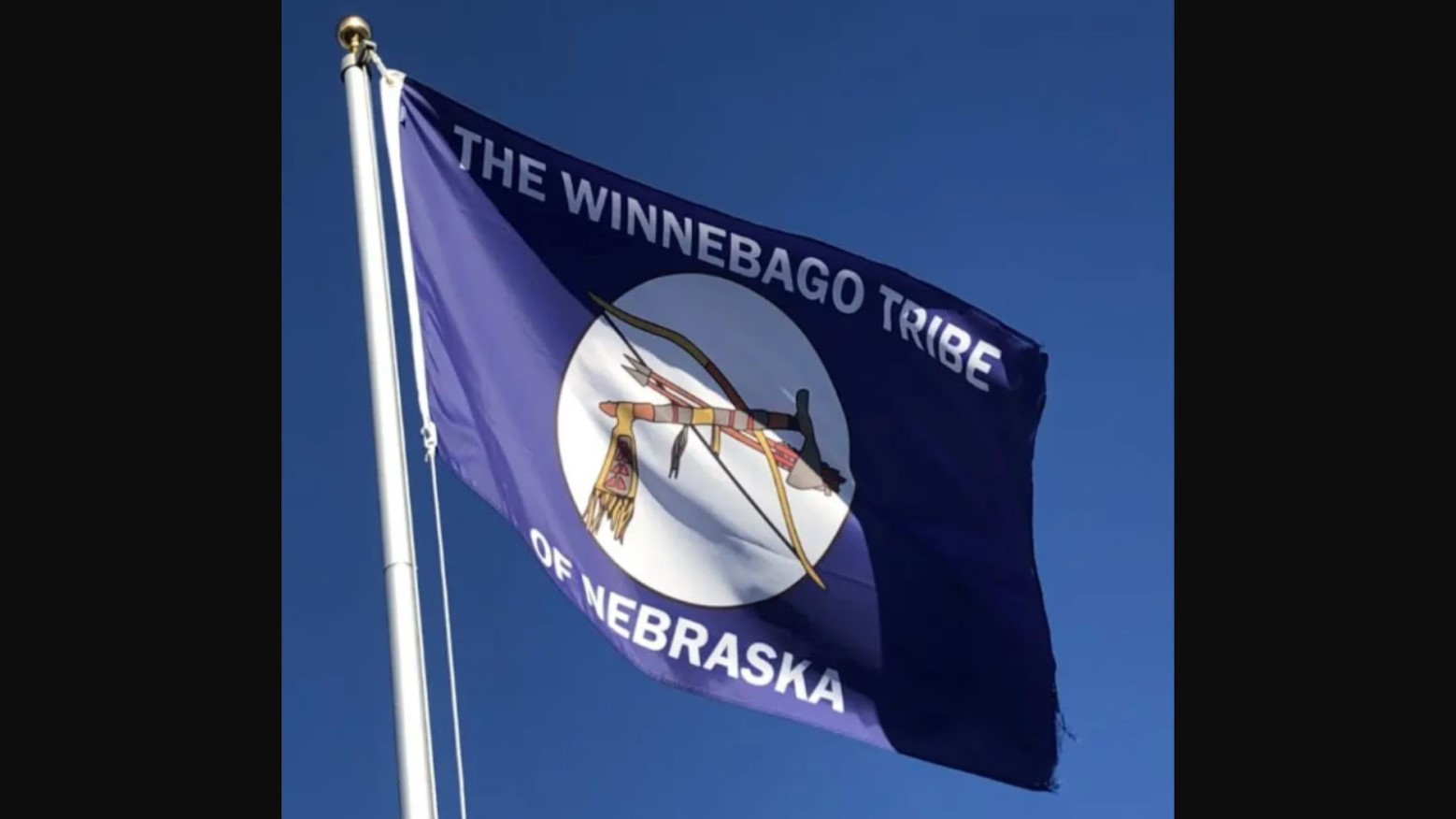 The Winnebago Tribe of Nebraska flag flies against a blue sky
