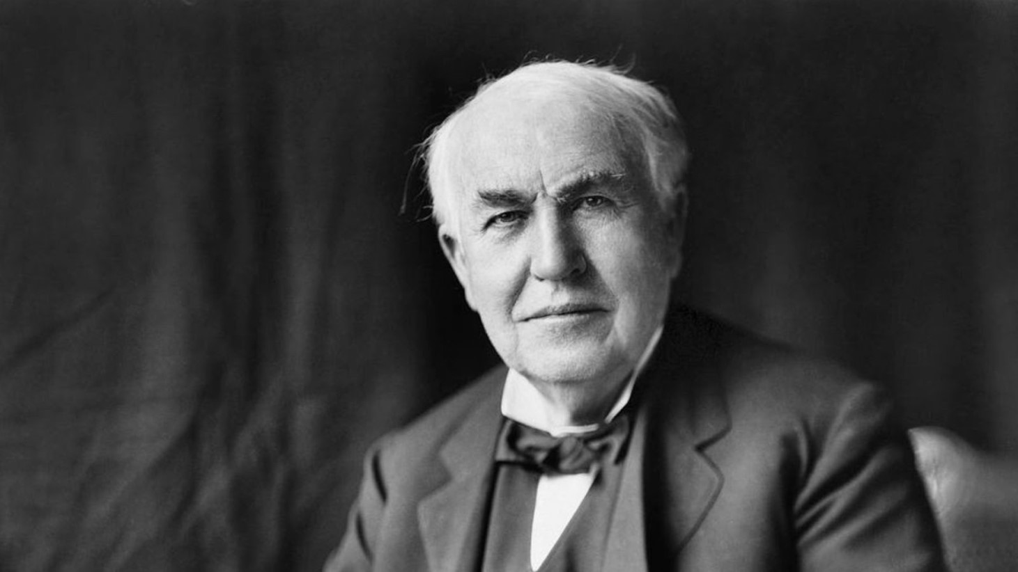 Black and white portrait of Thomas Edison, the renowned American inventor. Edison is shown as an elderly man with receding white hair