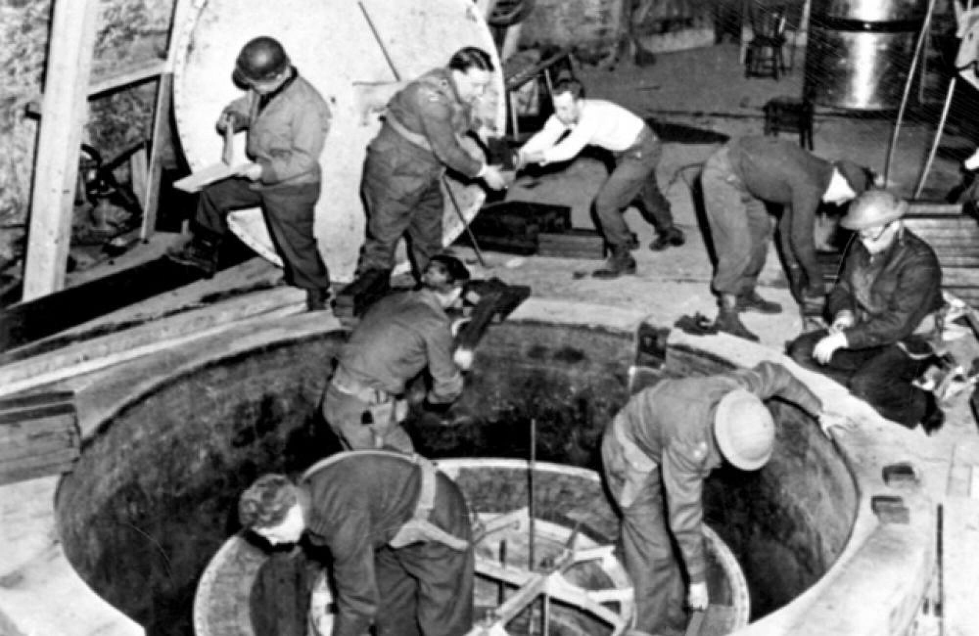 A grayscale image of a multiple men working on a nuclear reactor