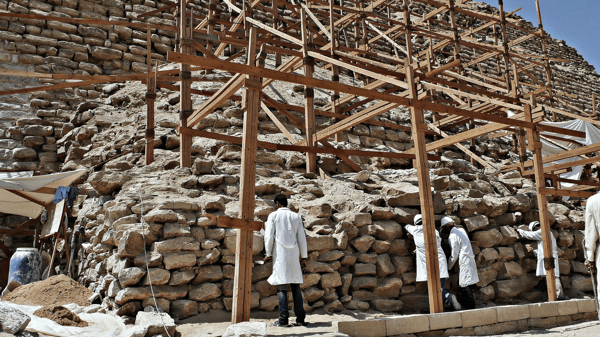 Specialists stand beneath scaffolding at the foot of the Djoser pyramid during the early stages of restoration efforts in 2007.