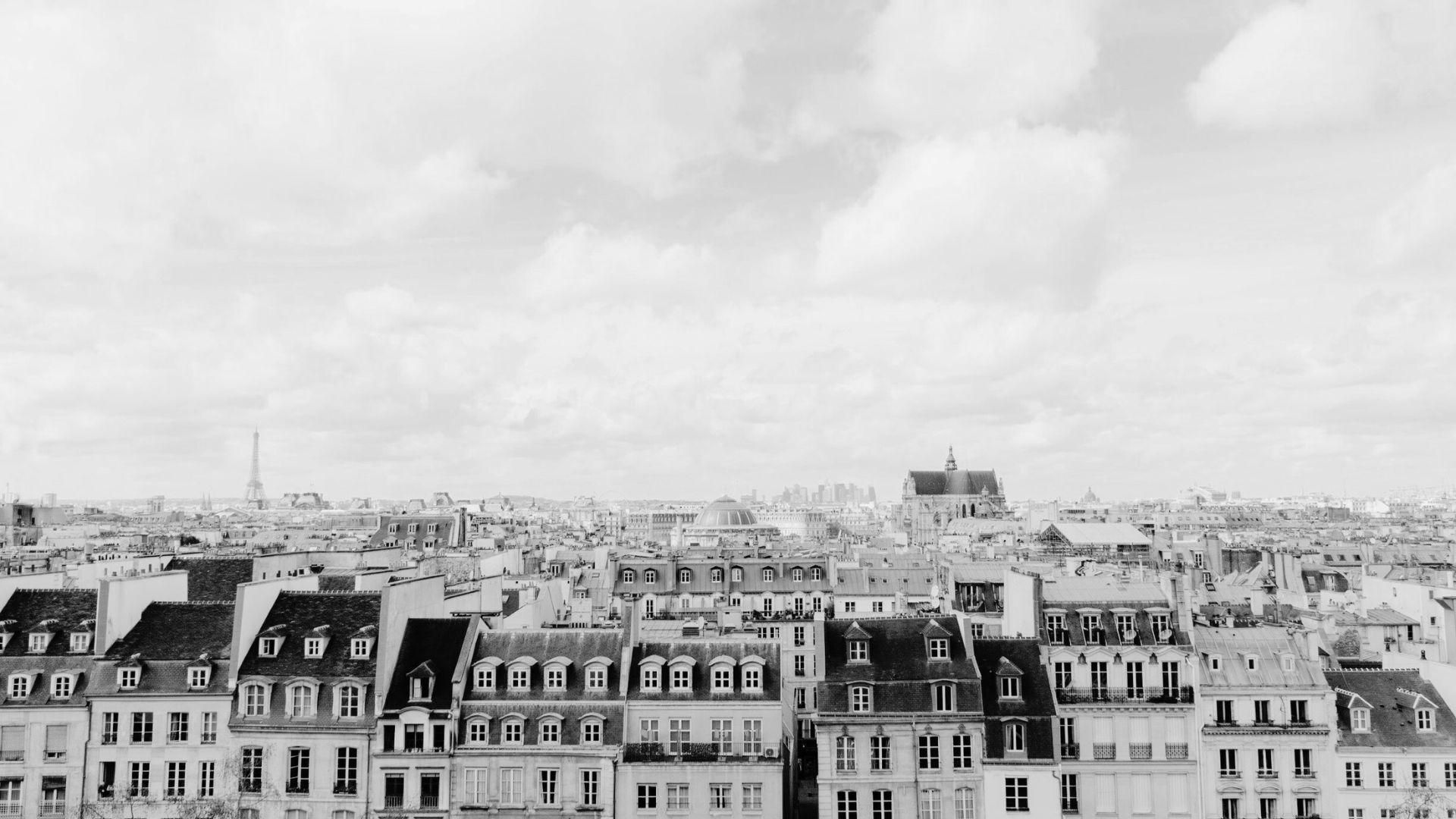 A black and white photo of the skyline of Paris, France, with a cloudy sky above.