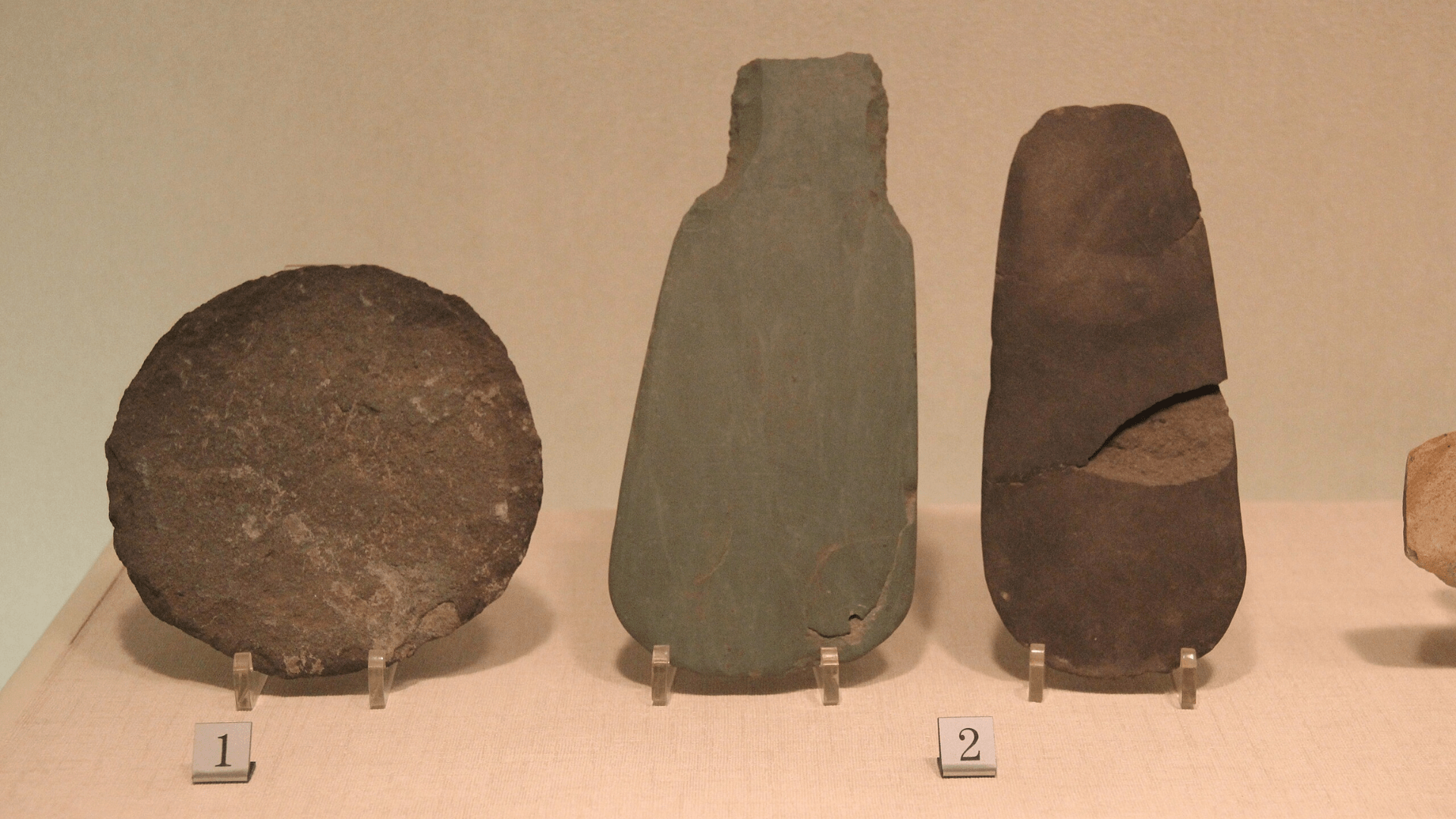 Stone tools in a row on display in a museum.