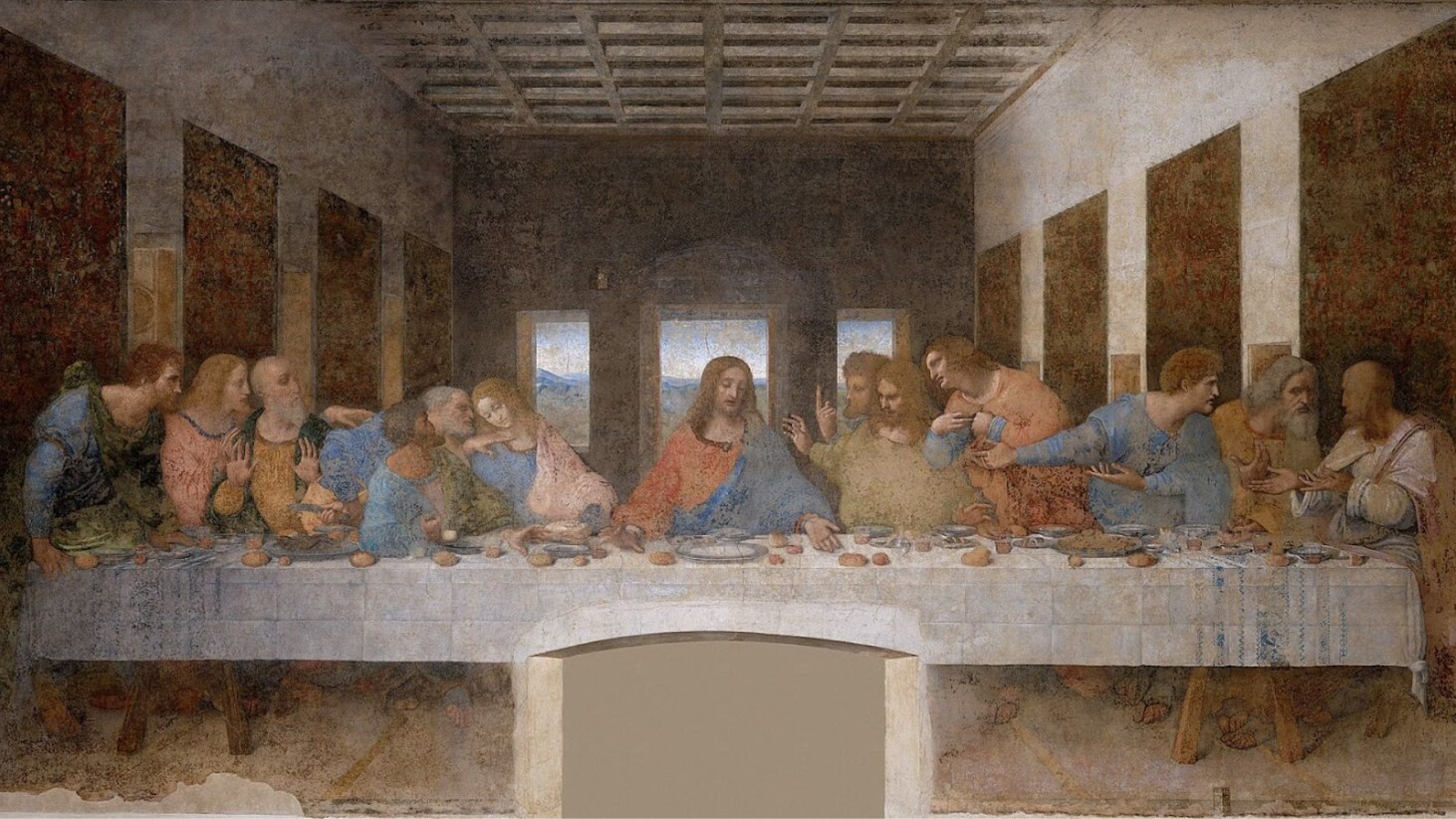 A wall fresco by Leonardo da Vinci, depicting the biblical scene of The Last Supper. The painting shows Jesus Christ at the center of a long table, surrounded by his twelve disciples