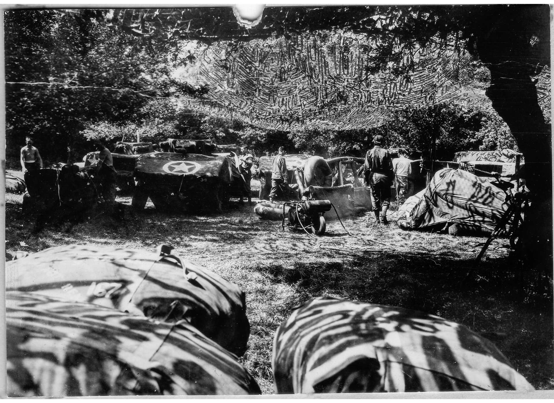 A gray scale image of a military unit lounging underneath trees