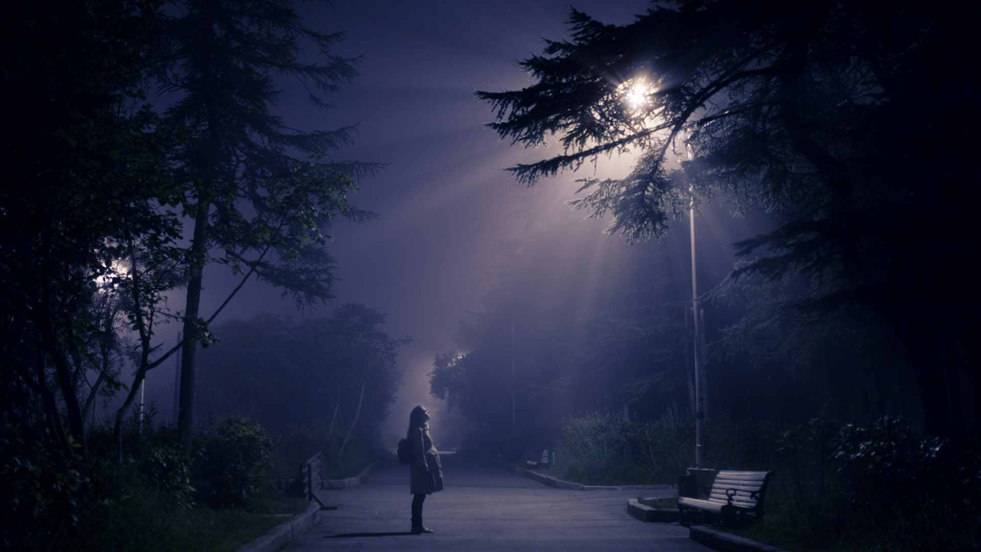 A person looking up into a streetlight meant to resemble lights from a UFO.