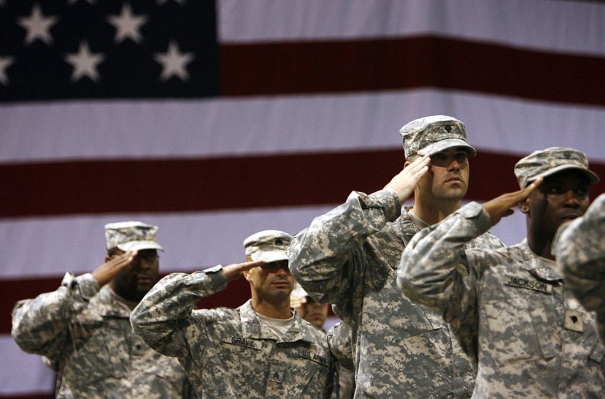Soldiers stand saluting during the national anthem for the redeployment ceremony at Marshall Army AirField