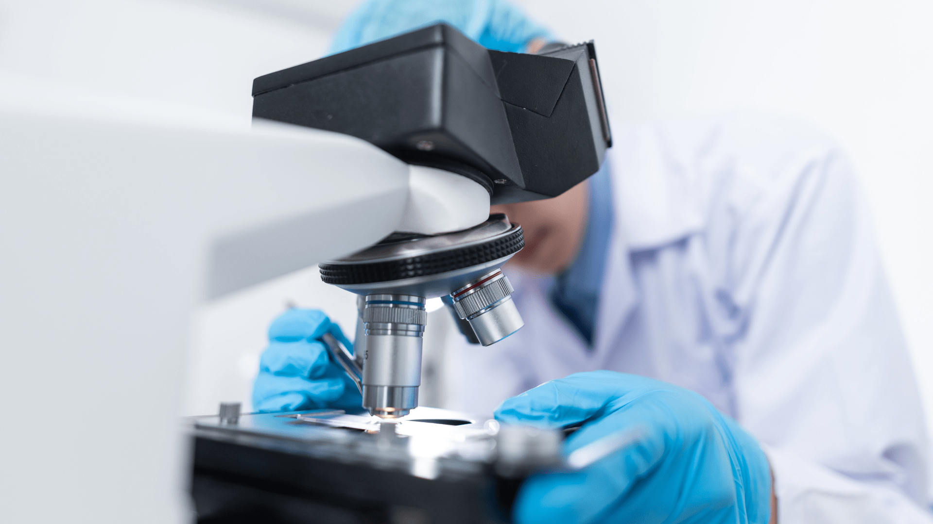 A scientist analyzing specimens under a microscope.