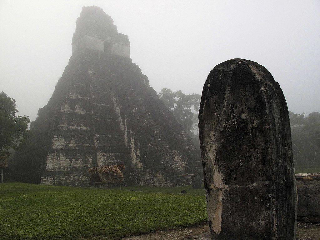 Morning fog covers the sky at sunrise over the Gran Plaza at the Tikal ruins in Guatemala