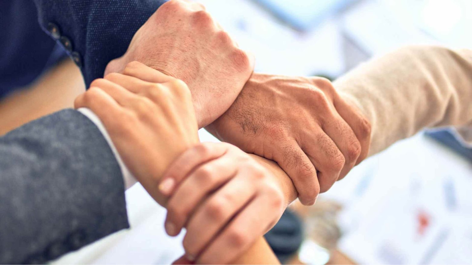 Three people crossing their arms together in support of one another.