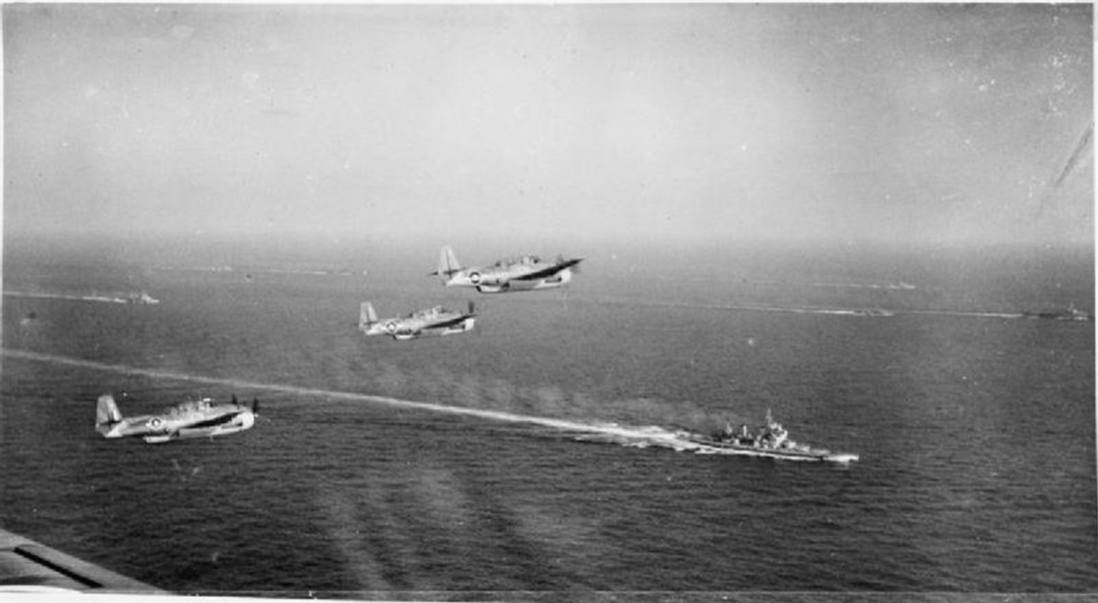 Three Grumman Avengers flying over the battleship HMS KING GEORGE V and other units of the British Pacific Fleet when on the way to attack Sakishima