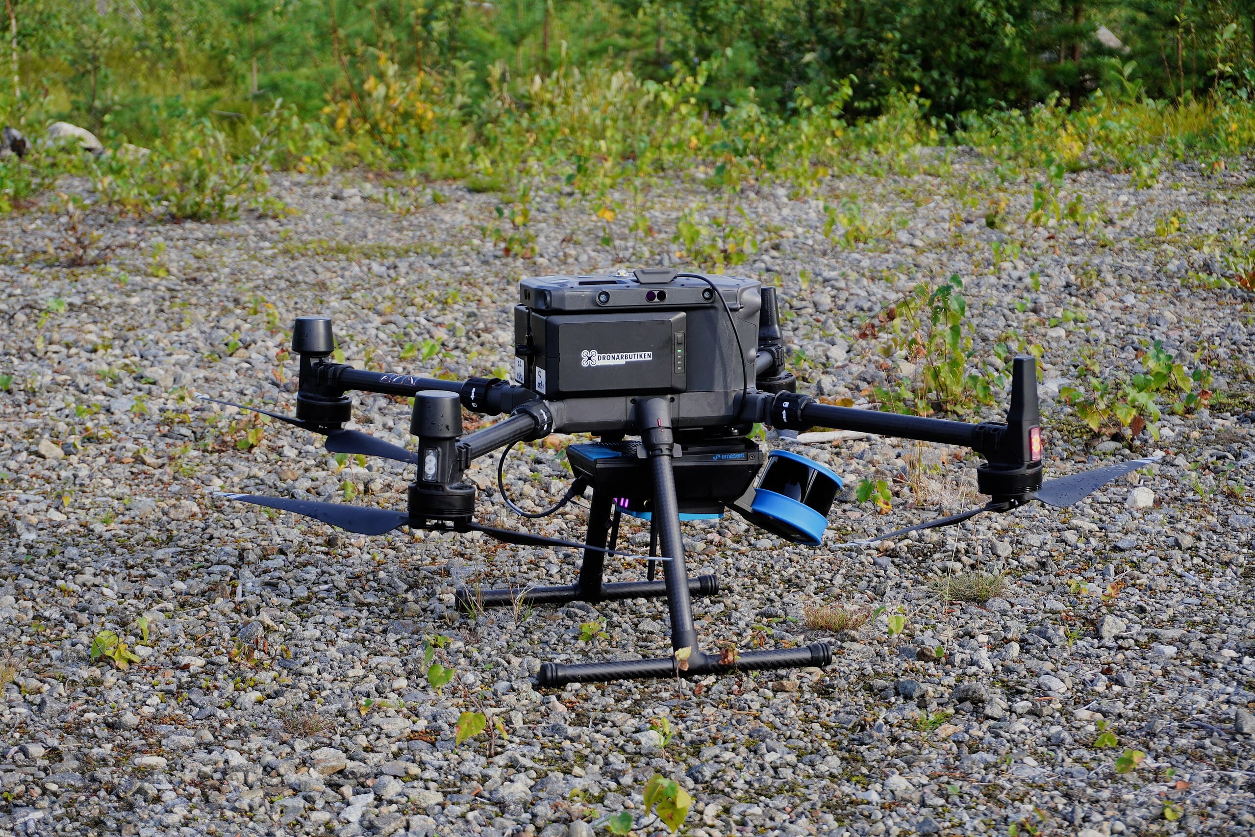 A drone with Lidar technology sitting at rest on gravel.