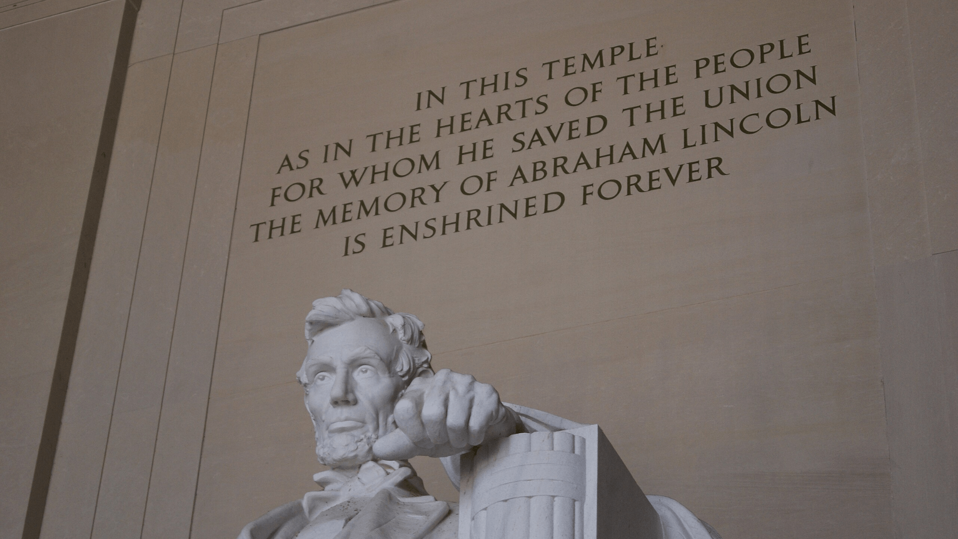 The Lincoln Memorial, showing the very top part of the sculpture that includes Lincoln’s head and left arm, and the quotation behind the statue reading “In this temple as in the hearts of the people for whom he saved the union the memory of Abraham Lincoln is enshrined forever.”