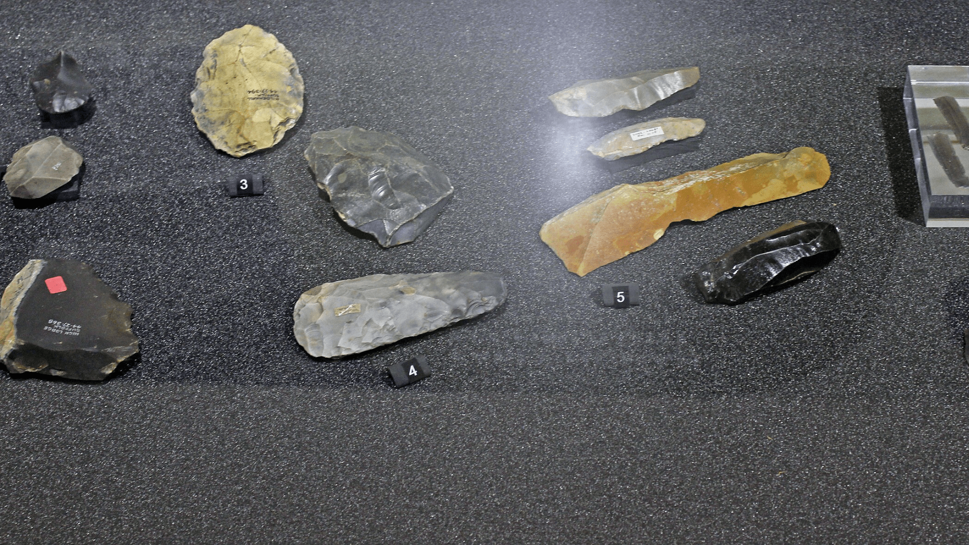Stone-age flint tools on display under glass in a museum.