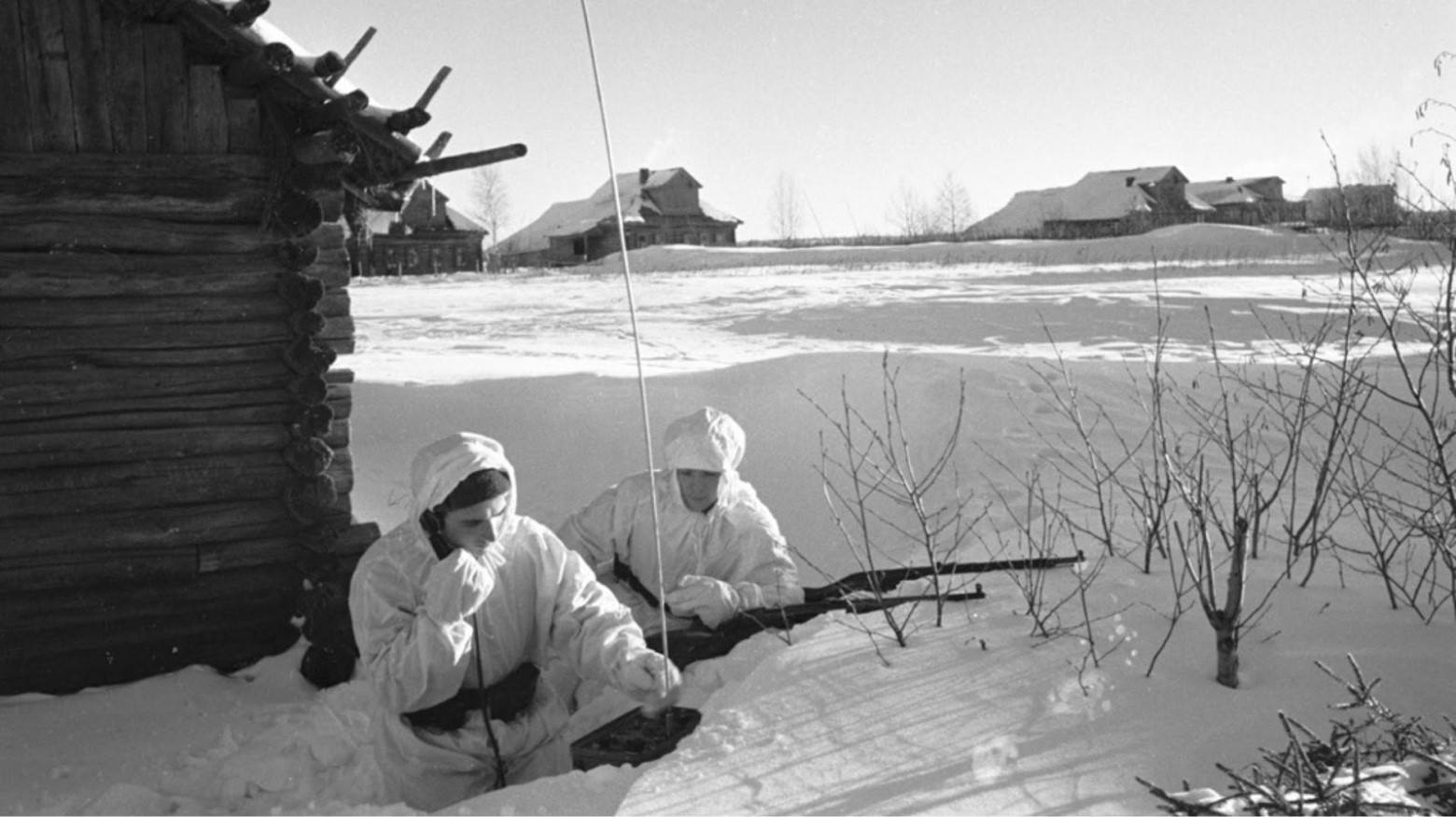 A black and white photo of two Soviet Union troops in all white sitting in snow in the winter during World War II.