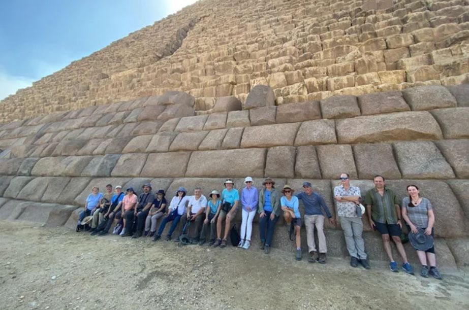 A photograph of a group gathered around the base of the Pyramid of Menkaure