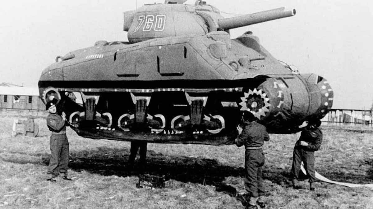 Four men lifting an inflatable tank off the ground