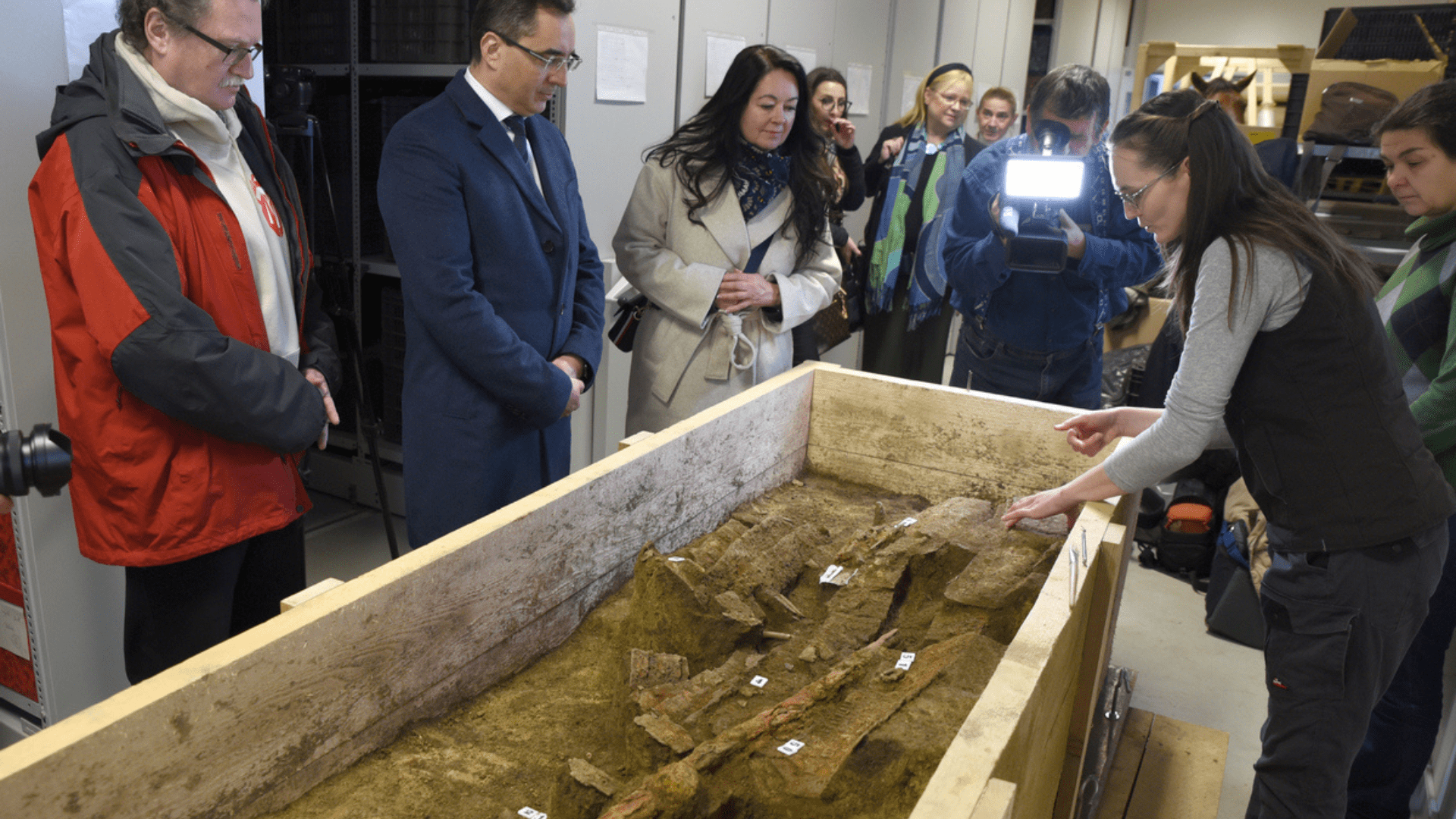 People gather around a wooden box holding the remains of a 7th-century Avar warrior.