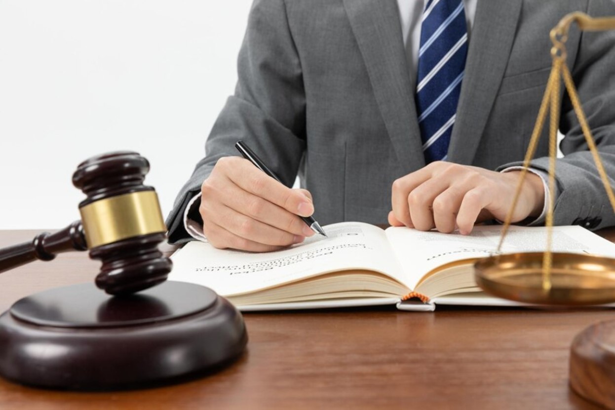 Lawyer fills out paperwork on a desk with a judges gavel beside him