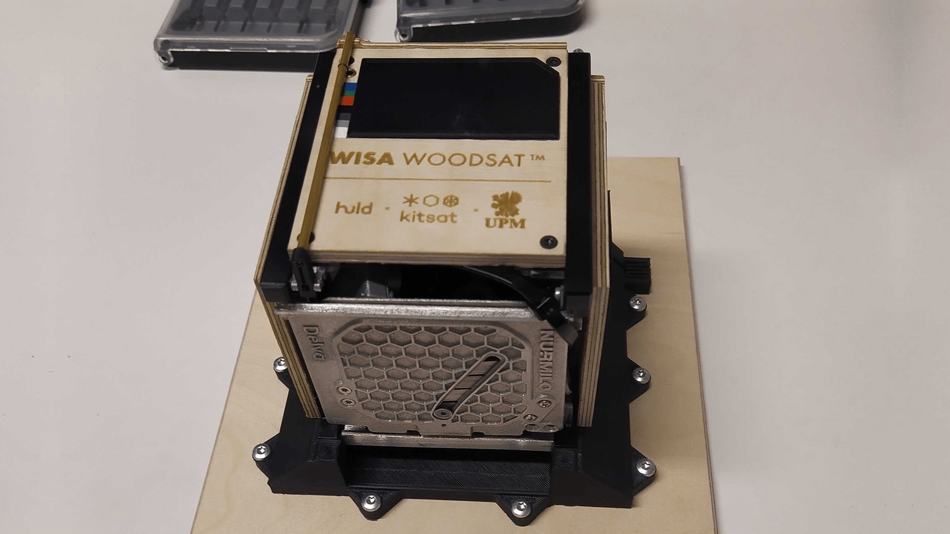 An engineering model of the WISA Woodsat wooden satellite sitting on a desk.