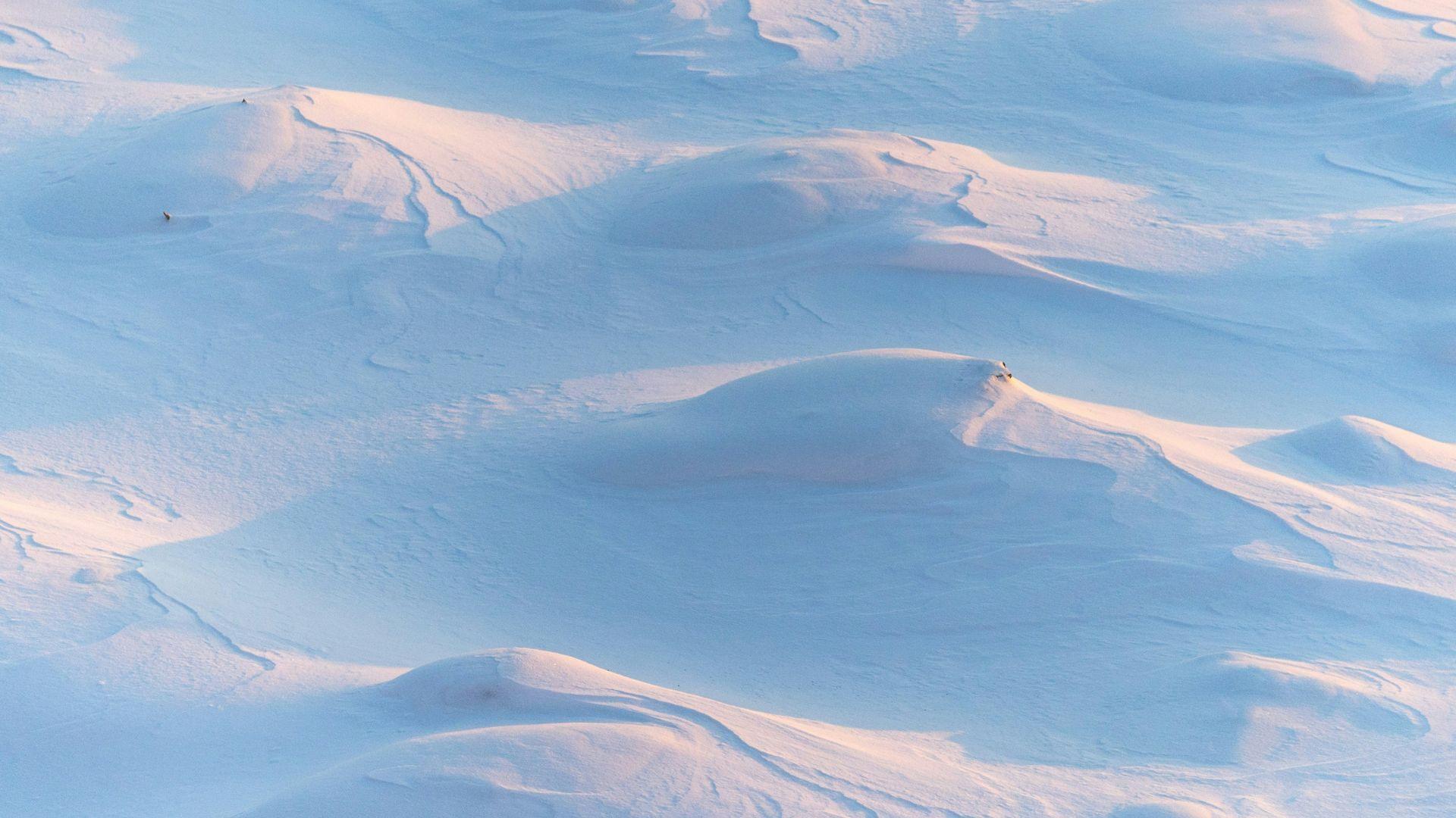 An aerial daytime view of blue and white snow-capped hills and mountains in Cherepovets, Russia.