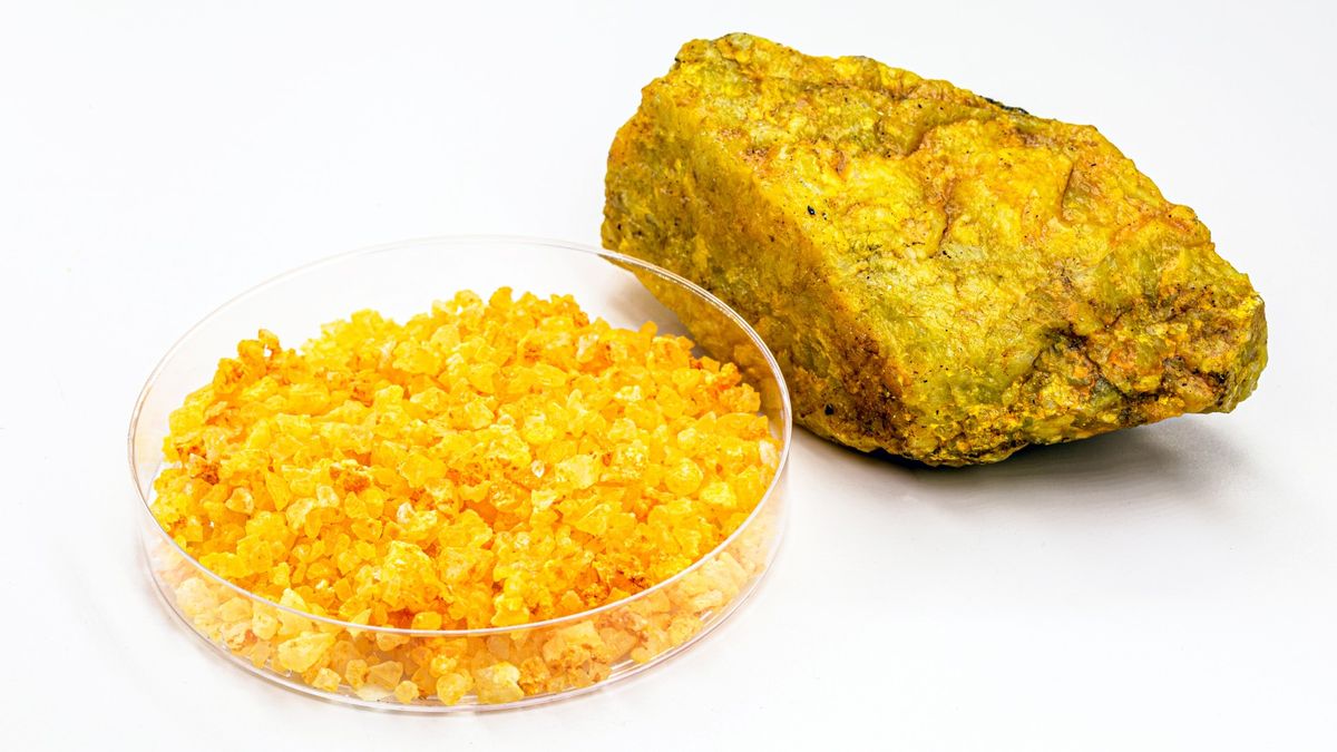 Uranium in a solid form and in a glass container on a white background