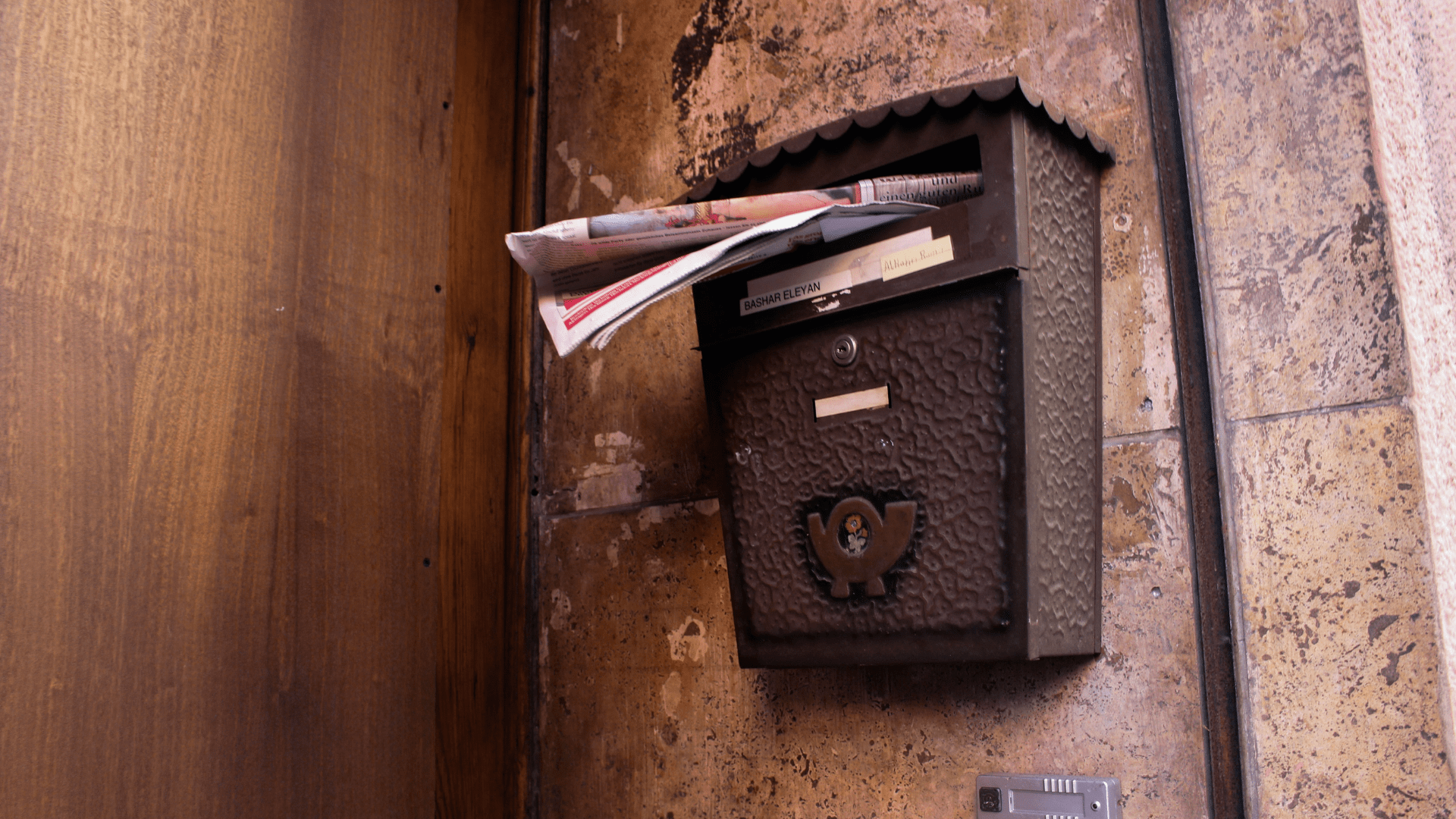 A mailbox on the wall filled with mail.