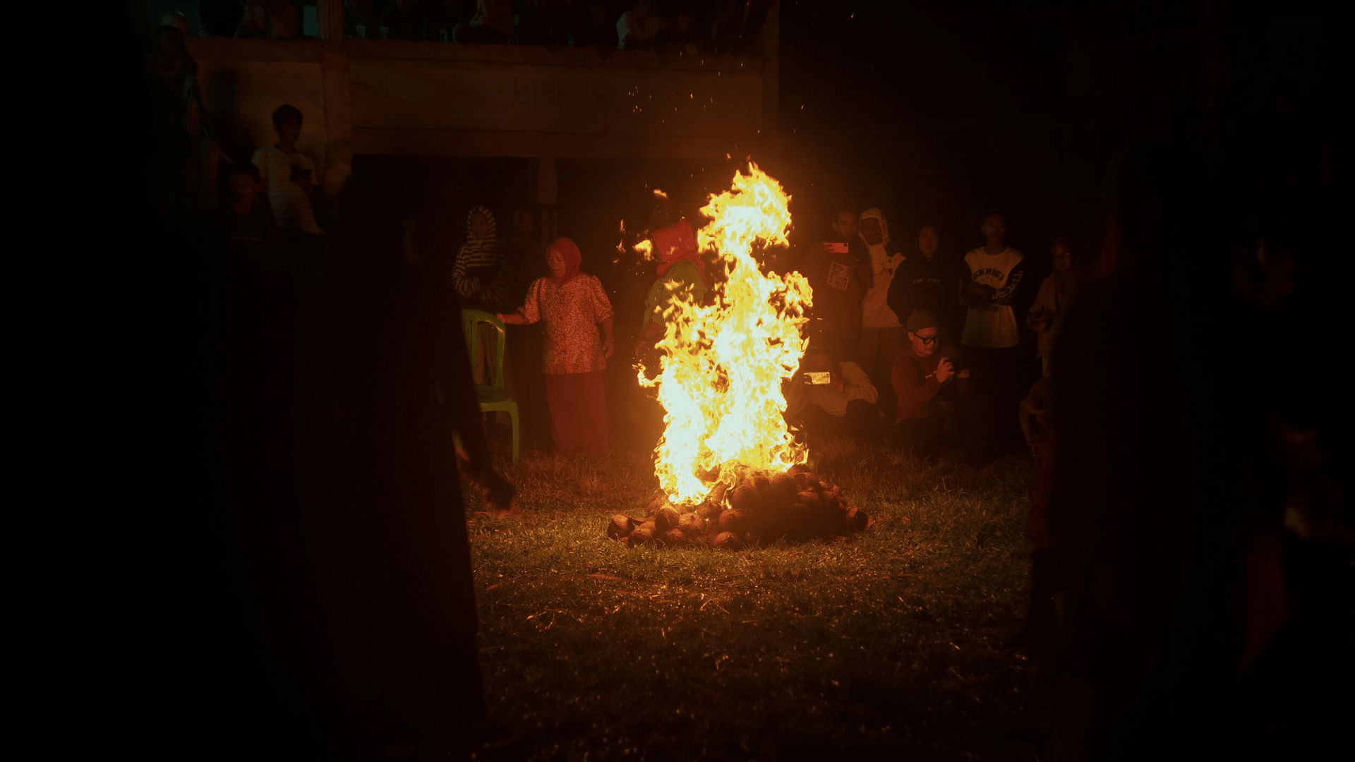 A large fire burns in the middle of a group of people.
