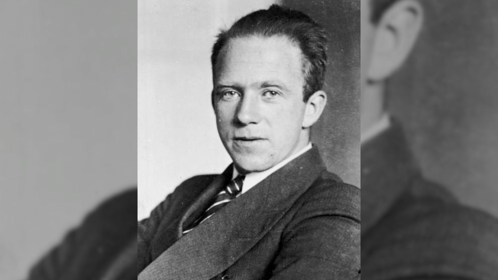 A grayscale headshot of a man in a suit
