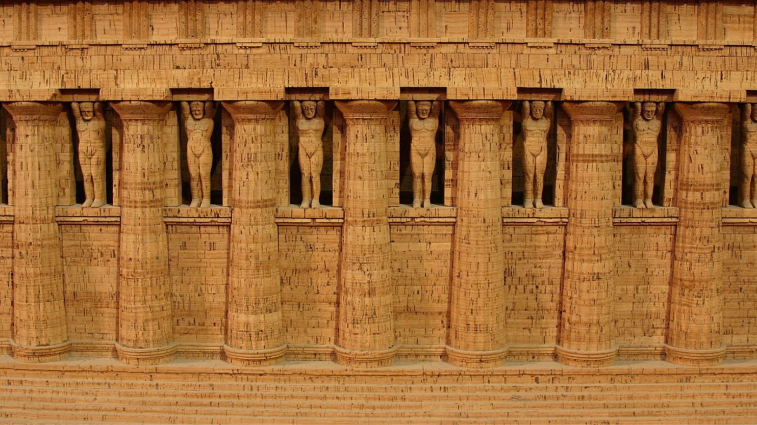 Side view of a Greek temple lined with columns and male statues.
