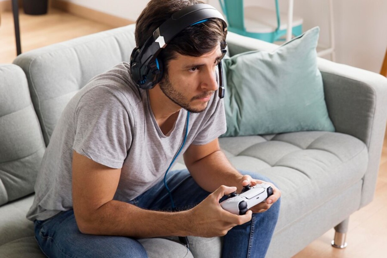 Man playing a video game on the couch with a headset on