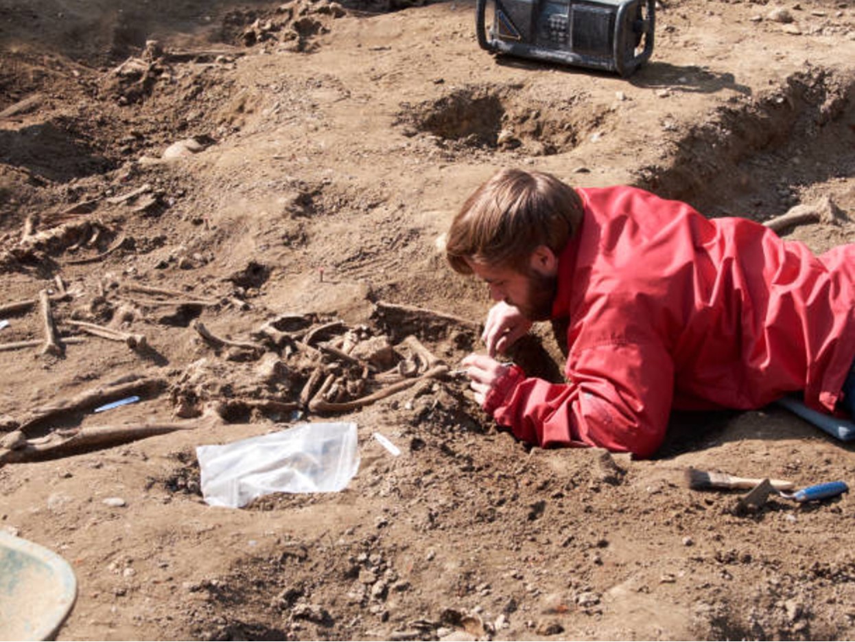 Paleontologist laying in the dirt studying bones