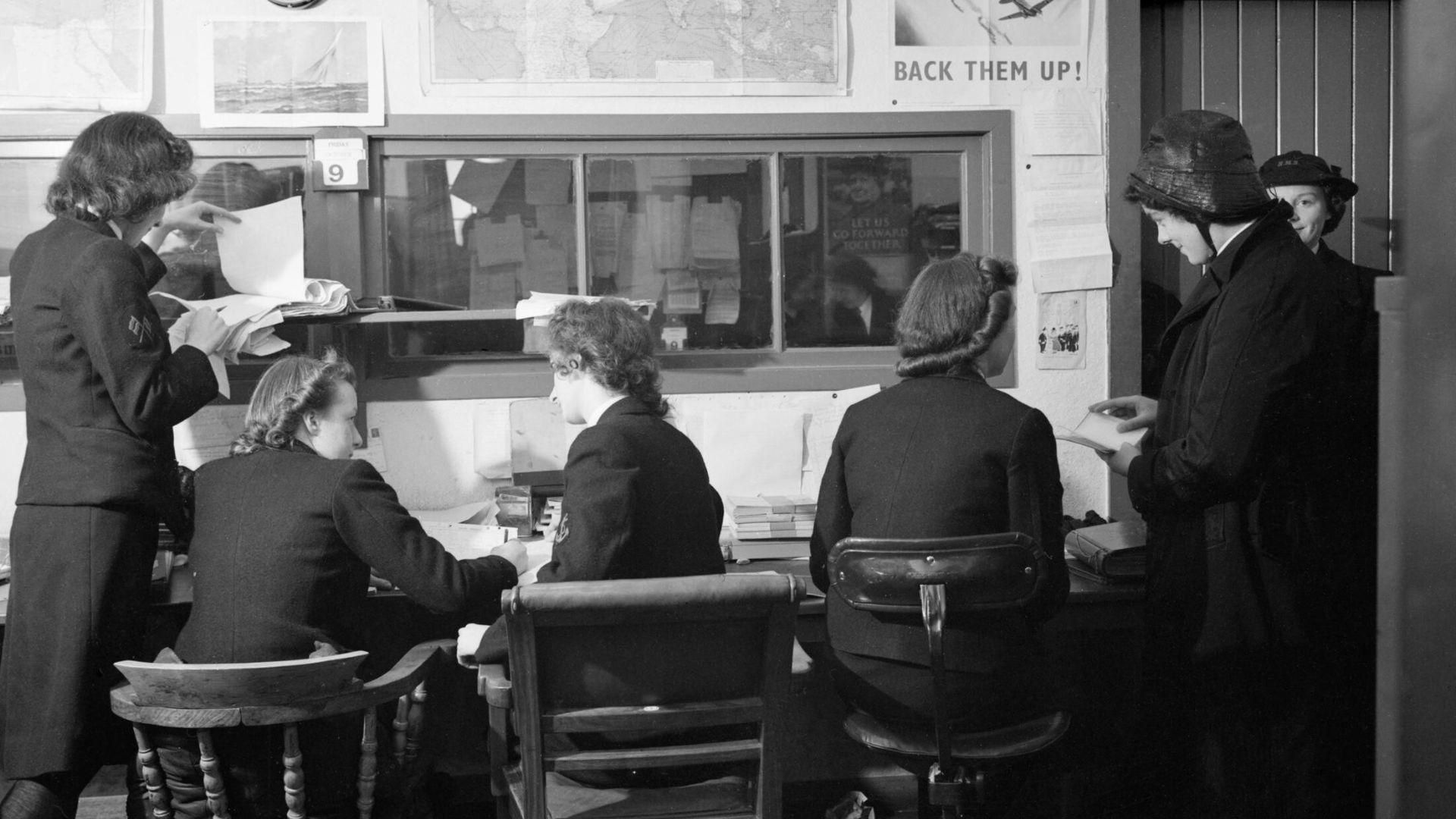 A black and white photo of a group of women transferring a code during World War II.