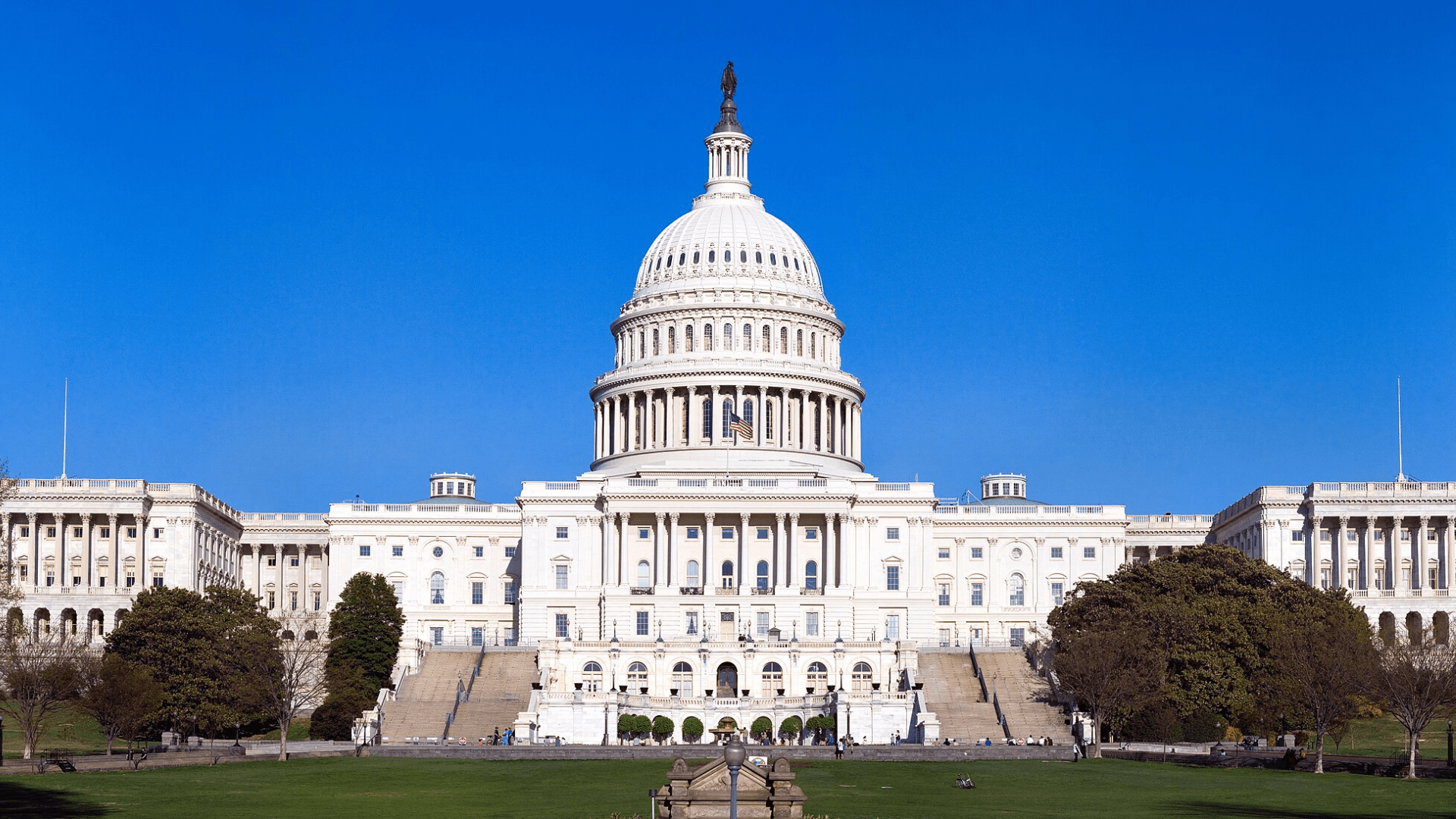The U.S. Capitol building photographed from across the front lawn on a cloudless day.