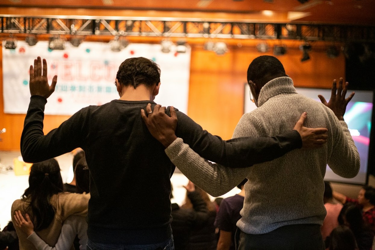 Two men holding each other by the shoulders and lifting their hands