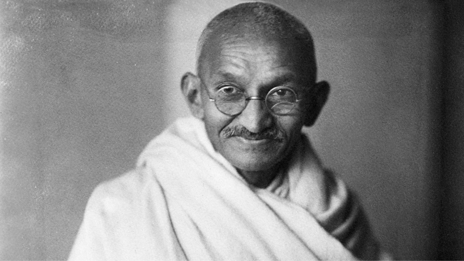 A black and white portrait photo of Mahatma Gandhi.