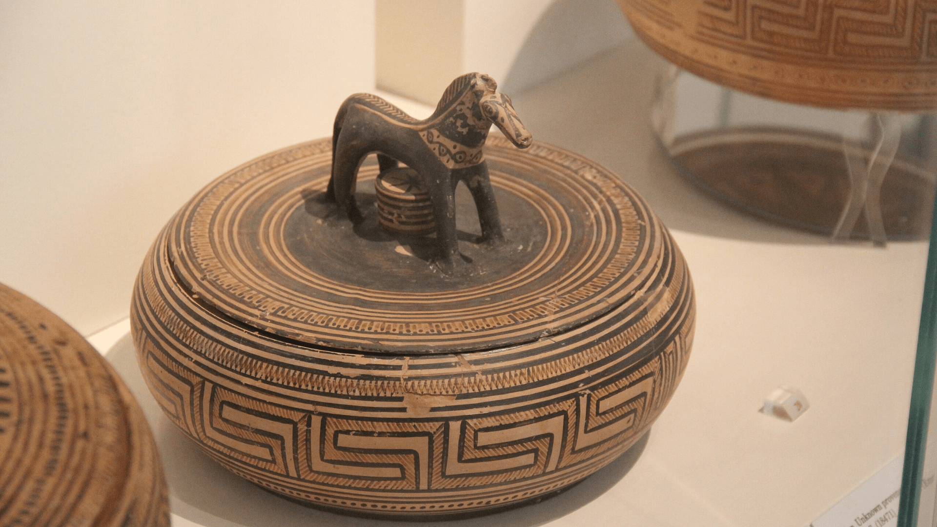 An ancient Greek vase in the National Archaeological Museum of Greece in Athens. The vase’s lid has a horse figurine as a handle.