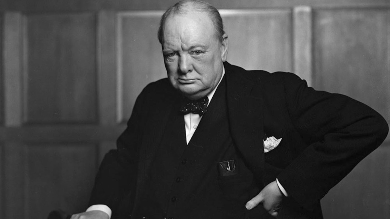 A black and white portrait of Winston Churchill in a suit.