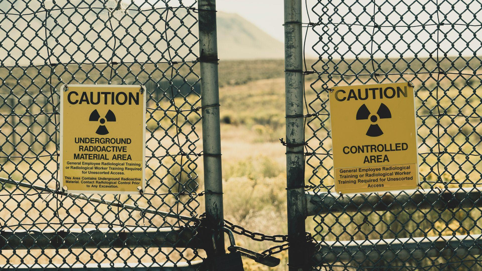 Two chain-linked fences with yellow and black radioactive warnings on them.