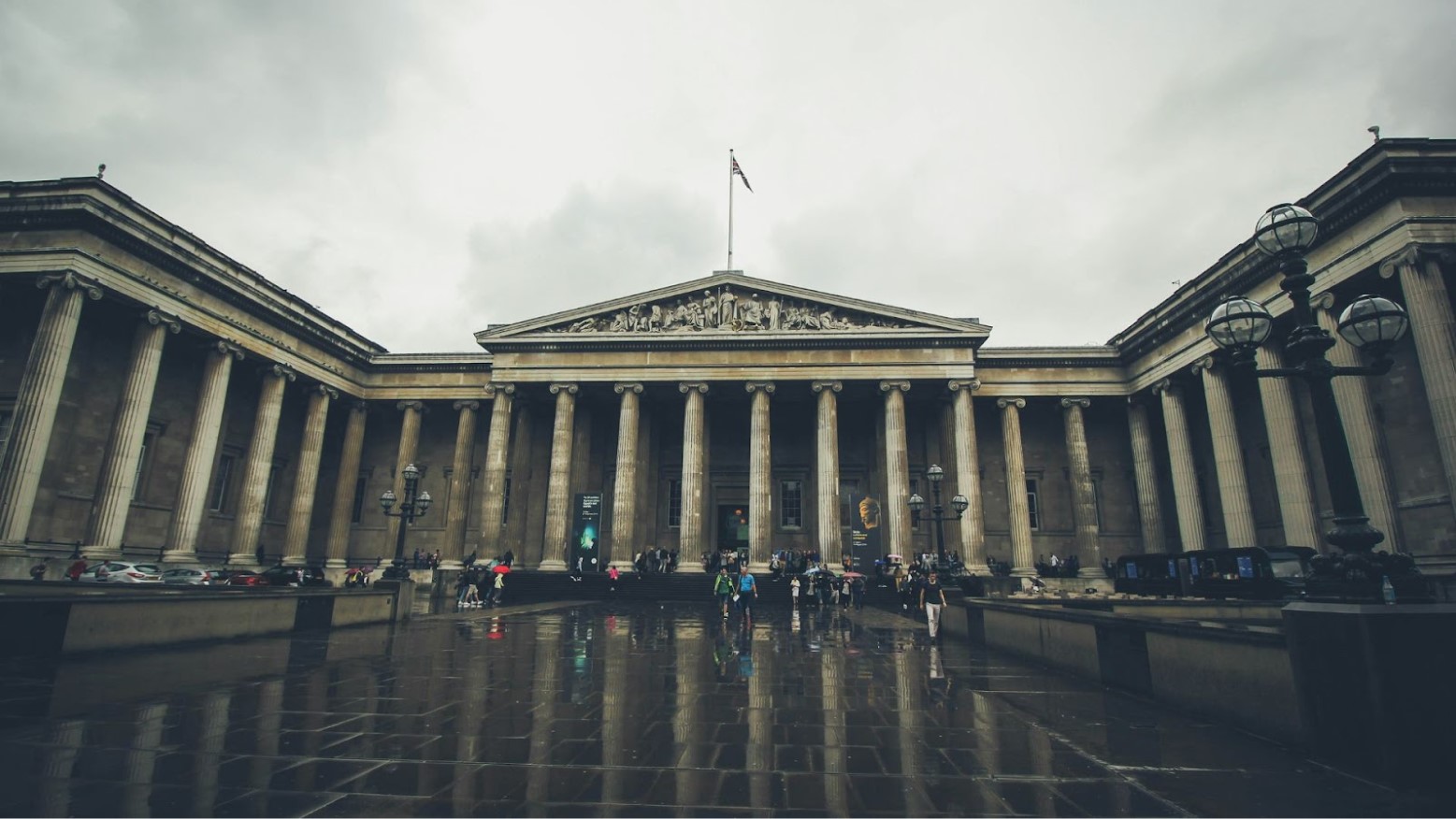 An exterior view of the British Museum as people walk into the building.