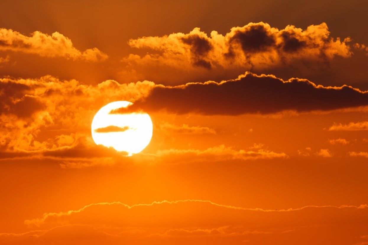 The sun sets in an orange sky